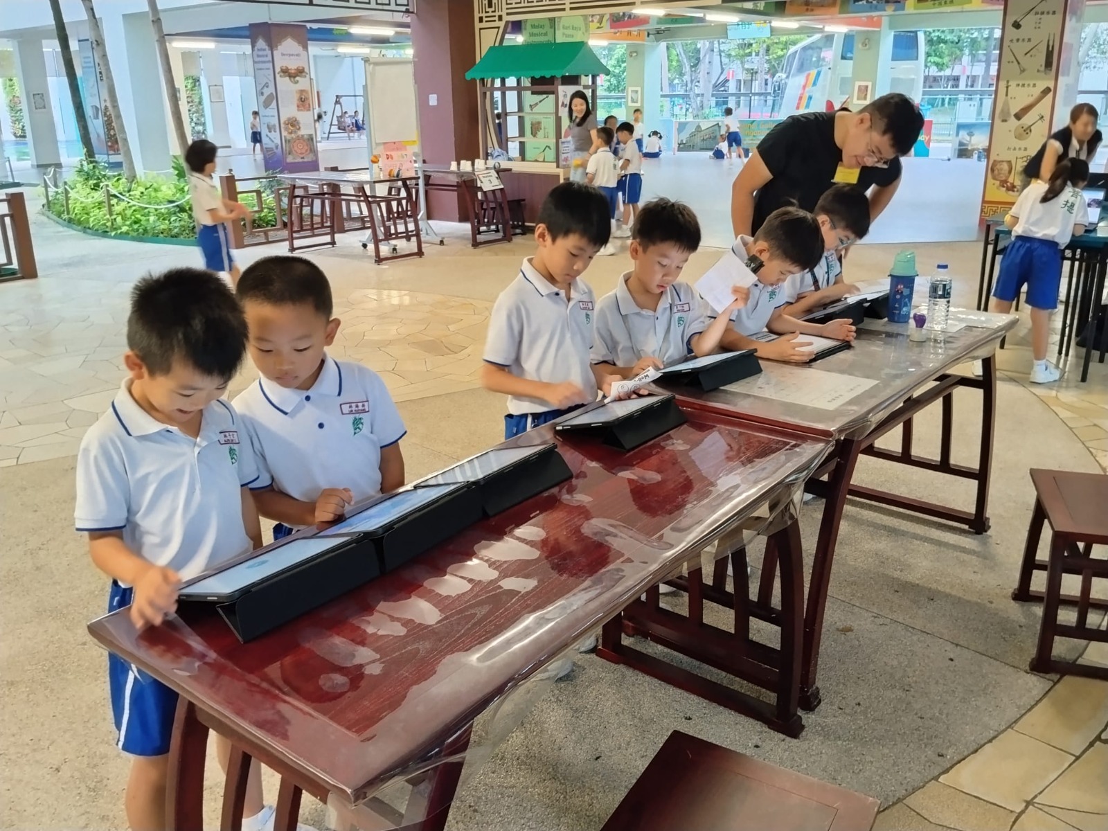 Pupils wearing Maha Bodhi School PE attire learning Cyber Wellness through iPads station.