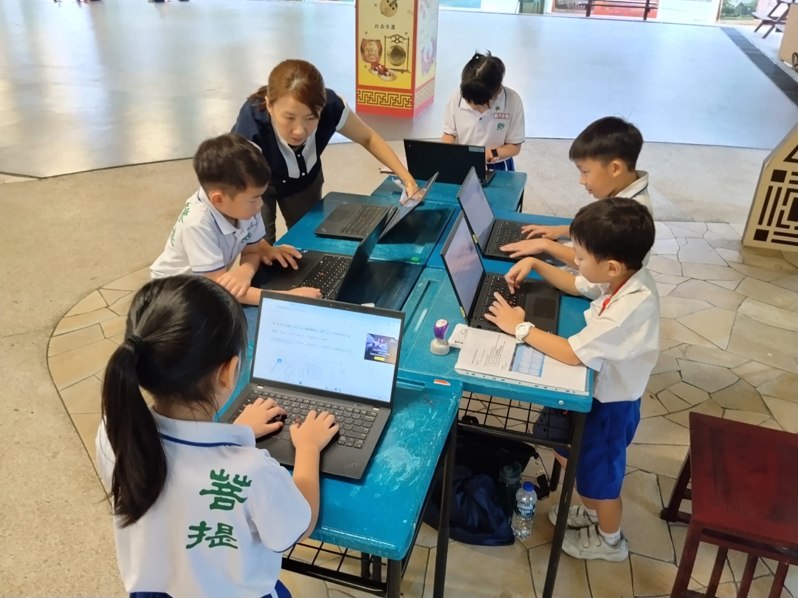 Pupils learning about Cyber Wellness through laptop station guided by parent volunteer.