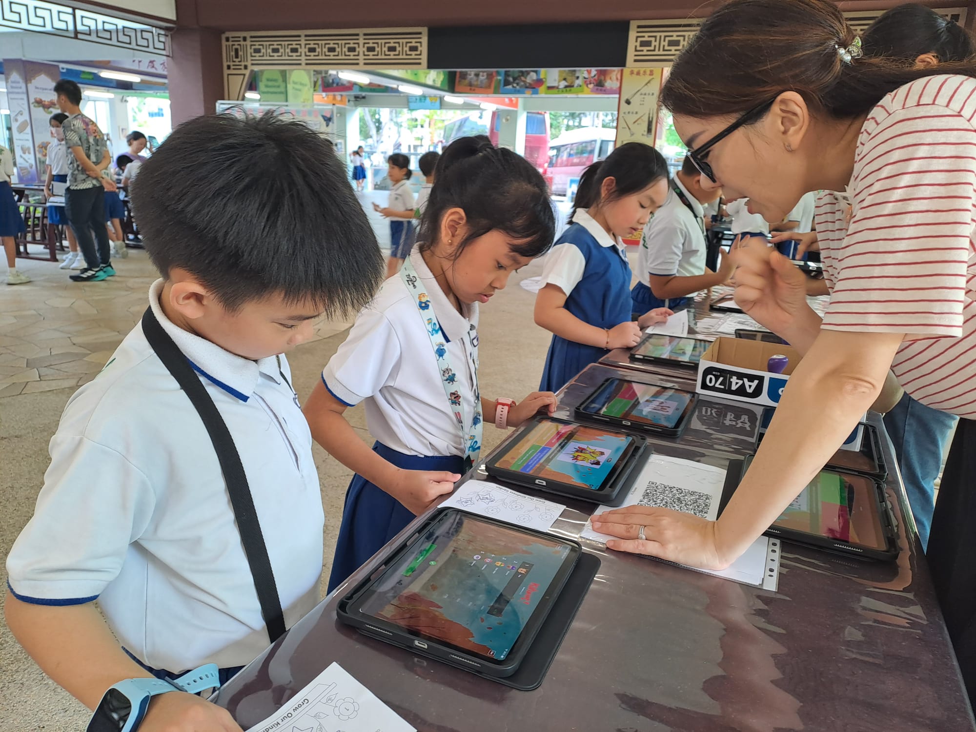 Pupils learning through iPads in school courtyard guided by parent volunteers