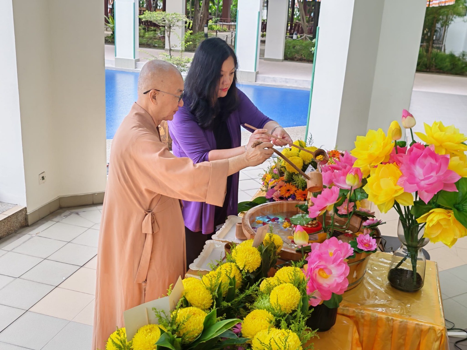 Venerable Seck Kwang Phing and Principal Mrs See Lai Kwan participating in Buddha Bathing Ceremony.