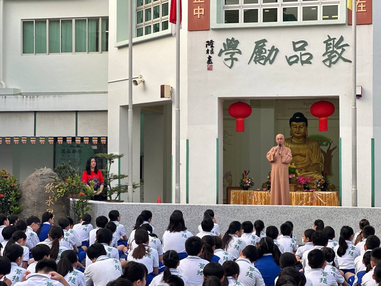 Pupils sitting in parade square listening to sharing by Venerable Seck Kwang Phing